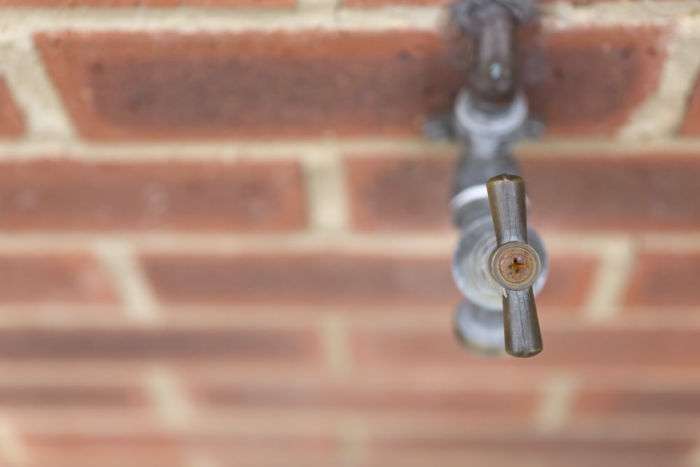 Detail of outside tap on a red brick wall