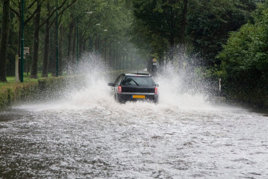 Image of a car driving through a flooded street
