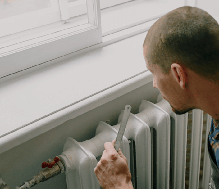Man with ruler next to radiator