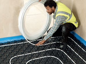 Worker installing underfloor heating pipe